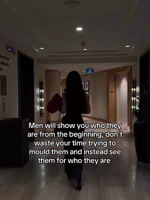 A woman with long dark hair is walking away from the camera down a hallway in an upscale-looking hotel. She is holding a bouquet of red flowers. The hallway is well-lit with recessed lighting and modern sconces. The text overlayed on the image gives dating advice.