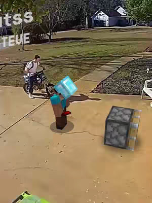A screenshot from a surveillance camera feed. In the foreground is a cobblestone path and a 3D rendered Minecraft character with a diamond block head and diamond block. Adjacent to it is a rendered stone block. In the background, a person in jeans and a white shirt with a backpack rides a motor bike while looking forward. A house, trees, and greenery is also in the background. Text overlays in the upper left corner.