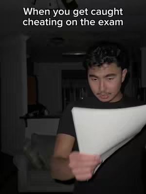 A young man looks down in what appears to be a dimly lit interior, holding a piece of paper. Overlayed at the top is white text. The composition suggests a moment of introspection or concern within an indoor setting.