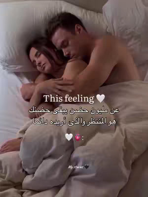 A couple is lying in bed under a white blanket. The woman is on the left, hugging the man who is on the right. Text overlays are present in both English and Arabic.