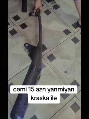 The cover image shows a person holding a black motorcycle exhaust pipe. The pipe is long and cylindrical with a curved end and mounting bracket. The hand is holding the pipe near the center. The background is a tiled floor. A text overlay in a white box with rounded corners is added with the message.