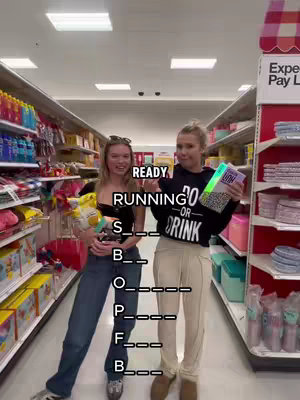 Two young women stand in a Target store aisle, posing for the camera. One holds a bag of chips, the other a glowing item, amidst shelves of products. Text overlays feature a fill-in-the-blanks game, framed with an orange and white checkered shelf.