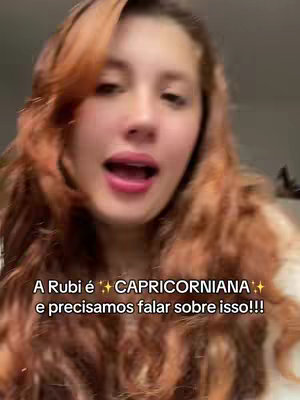 A woman with long, wavy auburn hair is shown from the chest up, looking directly at the camera with an open mouth expression, as if speaking. A text overlay at the bottom provides additional context in white capital letters against a soft, blurred background .