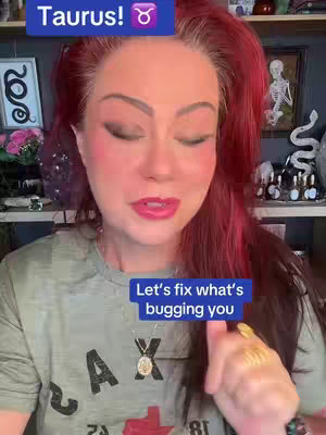 A woman with red hair, dark eye makeup, and pink lipstick is centered in a selfie-style video. She's wearing a green t-shirt with an off-white design and a gold pendant necklace. Two text overlays in blue boxes read "Taurus!" at the top left and "Let's fix what's bugging you" near the bottom of the frame.