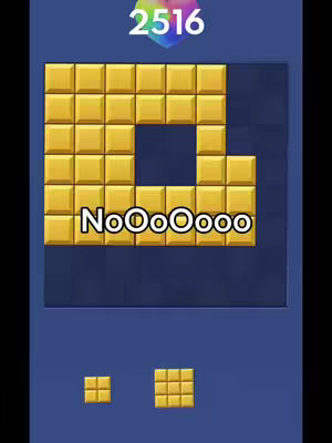 The cover image shows a gameplay screenshot of a block puzzle game. Large gold blocks fill the grid with a missing section in the middle. The text overlay displays the words 'NoOoOoooo'. Below, there are two smaller blocks representing available pieces, and at the top, a multi-colored gem and a numeric score, and underneath background is a uniform blue.