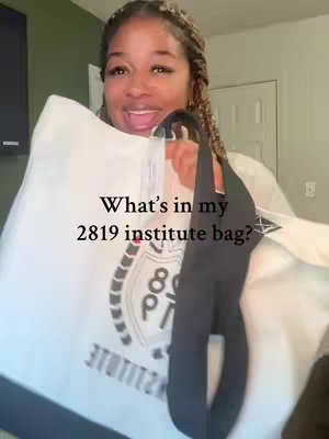 A woman with braided hair is holding a large white bag with a black strap. The bag has text overlayed, framed by the woman’s hands and body. She has a very expressive face, with her mouth open like she is speaking.