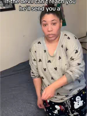A woman stands in a room with a bed in the background. The woman wears a light grey, long-sleeved shirt with black Mickey Mouse silhouettes and black and white pajama pants. She has a neutral expression. Text overlay on the top.