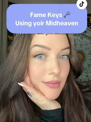 A close-up of a woman with long brown hair, blue eyes, and pink lipstick. She is holding her hand near her face, with a light blue rectangular text overlay above her head that reads "Fame Keys Using yoir Midheaven," and a small key icon. The background is blurred, and shows a glimpse of a decorative detail on the right.