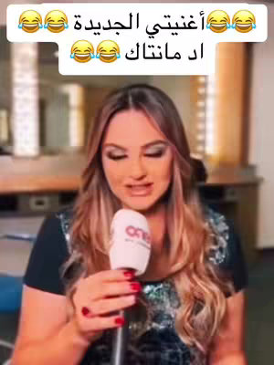 A woman is holding a microphone and speaking in this shot. She is wearing a black top, and has long wavy hair. She has red lipstick and eye makeup. Overlayed at the top is white text with emojis.