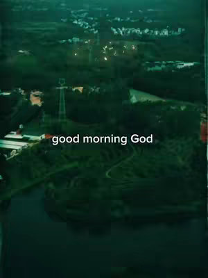 An aerial shot of a landscape, possibly a valley or a park, with a river or body of water in the foreground. The color palette is dominated by shades of green and dark blue, giving the image a slightly desaturated and moody feel. The text overlay 'good morning God' in a white, sans-serif font appears near the bottom.