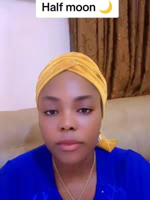 A woman with a yellow head wrap poses for the camera. She is wearing a royal blue top, and a chain. Above her head is a white rectangle with the words "Half moon", and a crescent moon.