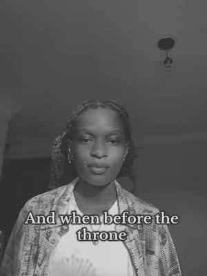 A black and white photo shows a person looking at the camera, with text at the bottom. The person has braided hair and is wearing light-colored clothing. The background is dark.