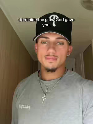 The cover image features a young man positioned in a hallway, facing the camera. He is wearing a black baseball cap, a gray long-sleeved shirt, and a silver necklace with a cross pendant. The text overlay says, "dont hide the glow God gave you."