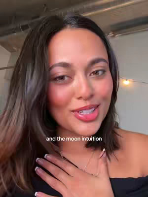 A close-up shot of a woman looking directly at the camera and speaking, with a soft background. She has dark hair and is wearing a black off-the-shoulder top. The lighting is warm, and there is text overlayed on the bottom of the image.