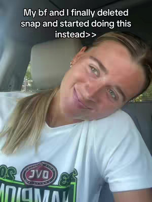 A woman with blonde hair in a ponytail smiles at the camera while partially obscured by the car setting. The text "My bf and I finally deleted snap and started doing this instead>>" is centered at the top in a white sans-serif font.