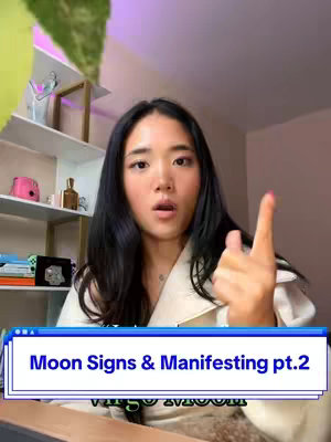 A woman with long black hair is in a room with a bookshelf background. She is looking at the camera with an open mouth, pointing one finger up, and has a visible overlay with text.