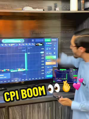 A man stands in front of a large monitor and a small laptop, both displaying charts and graphs. He points at the large monitor with one hand and holds a phone in the other. Overlay text says 'CPI BOOM' with emoji additions.