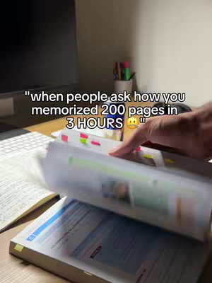The image shows a desk with a monitor, a book, and some stationary. A person's hand is flipping through the pages of a book, which is the focal point. The text overlay is at the top, offering context.