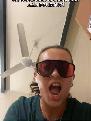 A woman in a green shirt and large sunglasses is shown with her mouth open as if in shock or excitement.