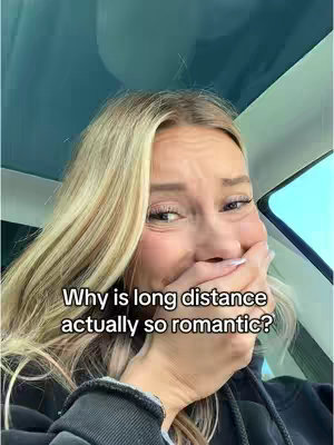 A woman with blonde hair is shown in a car, covering her mouth with her hand and appearing surprised, while text overlays ask why long distance relationships are so romantic.