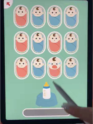 The cover image showcases a mobile puzzle game on an iPad screen. The game features cartoon illustrations of babies in swaddling clothes, some with happy faces and others crying, along with a baby bottle. The layout is simple with a pale green background and a neutral gray element at the bottom.