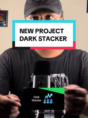 The image features a man in a black cap and shirt, positioned in front of a microphone. A rectangular overlay displays the text 'NEW PROJECT DARK STACKER' in white letters against a backdrop of light blue and dark red. Below the microphone is a business card showing the 'Dark Stacker' logo.