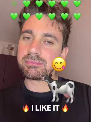 A man with a beard is shown with green heart emojis above him and a smiling emoji with a tongue sticking out to his right. A cow emoji is near his beard and below the image it says 'I LIKE IT'.