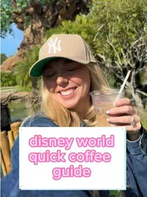 A woman with blonde hair and a beige baseball cap with a green brim, who is smiling while holding a cup of coffee with a straw. The background is of a lush, green outdoor setting.