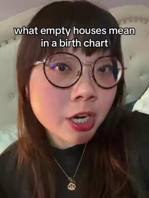 A woman wearing glasses is centered in the frame, looking directly at the camera and talking. Text overlays the image, with a light-colored bed in the blurred background.