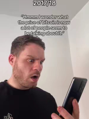 A man with short, dark hair and a surprised expression is looking down at a phone he holds in his right hand. His mouth is open, and his eyes are wide with astonishment. The background is a plain, off-white wall. Text overlays the image.