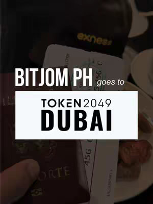 The image shows a close-up of a passport and tickets, with overlaid text. The background appears dark, possibly a plane interior. The main text elements are in white, framed by a white rectangle, and includes the words "BITJOM PH", "TOKEN2049", and "DUBAI". The overall composition suggests a travel or event-related theme.