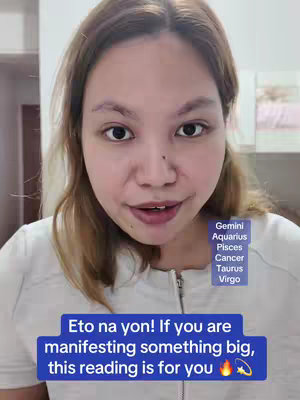A selfie-style video cover featuring a woman in a white top. She has brown hair and is looking directly at the camera with a neutral expression. Behind her is a neutral, indoor setting. Overlayed text in a blue box at the bottom reads, "Eto na yon! If you are manifesting something big, this reading is for you." with an emoji. To the right of the woman is a rectangle listing zodiac signs in a colored box.