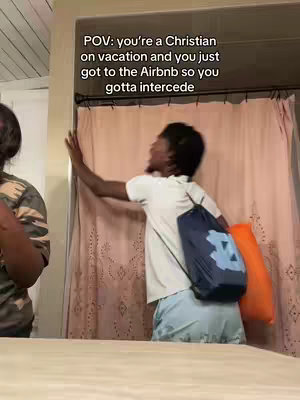 A person, wearing a white t-shirt and light blue shorts, is shown in a bathroom, reaching towards a shower curtain. The image has text overlayed that says "POV: you're a Christian on vacation and you just got to the Airbnb so you gotta intercede."