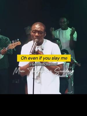 The cover image captures a live performance scene. A Black man with short hair, dressed in a white long-sleeved shirt, is positioned in the foreground, centered, singing into a microphone. He's the focal point, with a focused expression, likely mid-song. Behind him are several other figures, partially visible, likely choir members or other performers. The lighting appears to be a stage setup, with dark background. A yellow rectangle highlights text and the creator's name.