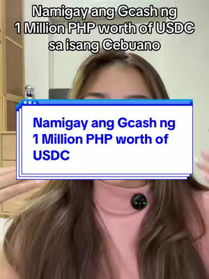 A selfie-style video cover image featuring a woman centered. She has long, light brown hair and is wearing a pink turtleneck. A graphic overlay in a Windows-style frame, with a blue header and white content, is visible. The text on the overlay reads: "Namigay ang Gcash ng 1 Million PHP worth of USDC". The background appears to be a room with neutral-colored walls and a cabinet visible on the left.