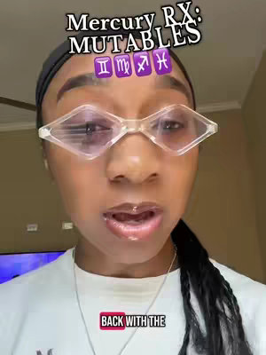 A close-up of a person with light skin wearing clear, diamond-shaped glasses. At the top of the frame, there is text that reads 'Mercury Rx: MUTABLES' above four zodiac symbols; the person appears to be speaking with visible lip gloss. Below, there is text that reads 'BACK WITH THE'. The background is out of focus, suggesting an indoor setting.