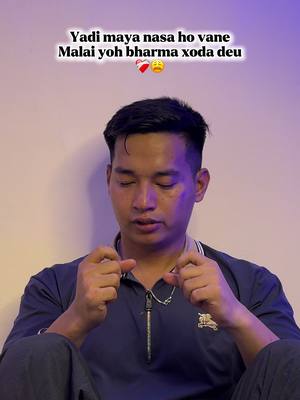 A young man with dark hair, wearing a navy blue shirt, is the central focus. He is sitting, with his hands clasped together in front of him. A text overlay at the top of the image features text in what appears to be a non-English script. The background is a muted, neutral white.