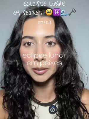 The cover image is a selfie of a person with long, dark, wavy hair. In the background is a light gray wall. Text overlays at the top and bottom of the image reveal information about a lunar eclipse in Pisces, with emojis and the date. The person is looking directly at the camera with a neutral expression. She is wearing a black and white top.