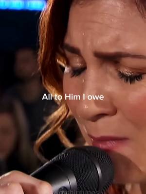 The cover image is a close-up shot of a woman's face. She has fair skin and reddish-brown hair. Her eyes are closed, and there are visible tears and glistening on her face, suggesting she is emotional. She holds a microphone close to her mouth. The background is slightly blurred, with soft lighting. Text overlay adds "All to Him I owe" in white.