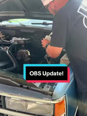 A man working on the engine of a classic Chevy truck. The hood is up, revealing the engine compartment. The man is wearing a white cap and black shirt and appears to be working on the master cylinder. A colorful text overlay at the bottom center reads 'OBS Update!'.
