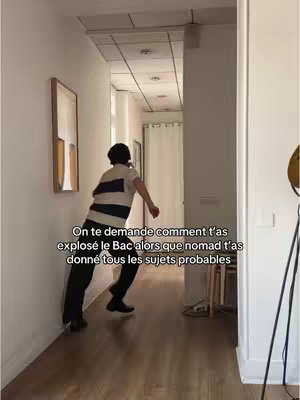 A person in a black and white striped shirt and black pants leans against a white wall in a hallway, seemingly running or falling. Text overlays the image.