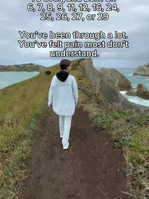 A person walks away from the camera on a trail along a cliff. The path is made of dirt, and the cliff face is rocky. The sea is visible on the right side, with a cloudy sky above it. Text overlays on the photo are arranged in a layered way.
