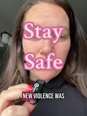 A selfie-style video, featuring a woman's face in close-up. The image is dominated by a pink overlay reading 'Stay Safe,' partially obscuring her face. She is holding a small black device - possibly a vape - and the text 'NEW VIOLENCE WAS' is overlaid beneath the device. The background features a room with a light fixture visible.