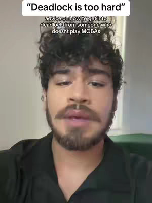 A man with curly brown hair and a mustache and beard in a black shirt is in the center of the image. The image has white text above the man's head.