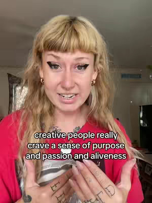 A person with blonde hair and bangs is the central focus of the image, they are wearing a red top and has distinct black eyeliner, gold earrings rings and a nose ring. The background is a room. The person is speaking, with the text overlayed at the bottom of the image.