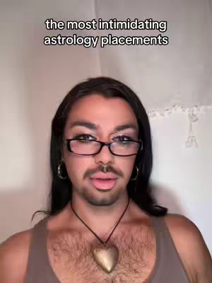 A person with makeup and glasses is centered in the frame. Above them is text, white curtains are behind them.