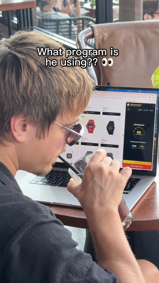 A man sitting at a table in a cafe uses a laptop. He is using a web scraping tool, as evidenced by the on-screen interface showing a countdown and extracted data. The laptop is open, displaying a website with a product selection of watches. The man is drinking a beverage through a straw.