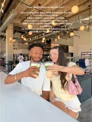 A photograph shows a man and a woman, both smiling and holding drinks. The man has dark hair and is wearing a white t-shirt. The woman has dark hair and is wearing a light-colored top and a pink purse strap on her shoulder. They are at a bar or cafe, and there's text overlaid.