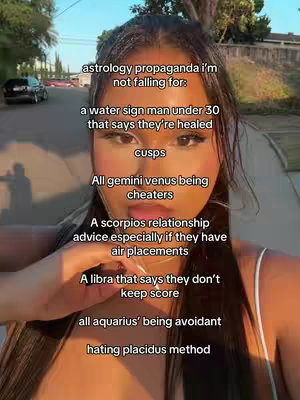 A young woman partially obscures a selfie. The text 'astrology propaganda i'm not falling for' is overlaid, followed by a list of astrological dislikes. The woman is fair-skinned with dark hair and a light-colored top, with an outdoor, slightly out-of-focus background.
