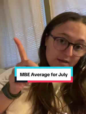 A person with glasses points their index finger up while a text overlay states the MBE average for July. The person is in a well-lit indoor setting.